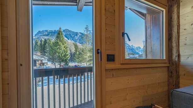 Eine Holzhütte mit einem Balkon mit Blick auf eine verschneite Berglandschaft.