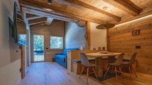 Ein Interieur einer Holzhütte mit Essbereich, einer Couch und einem großen Fenster.