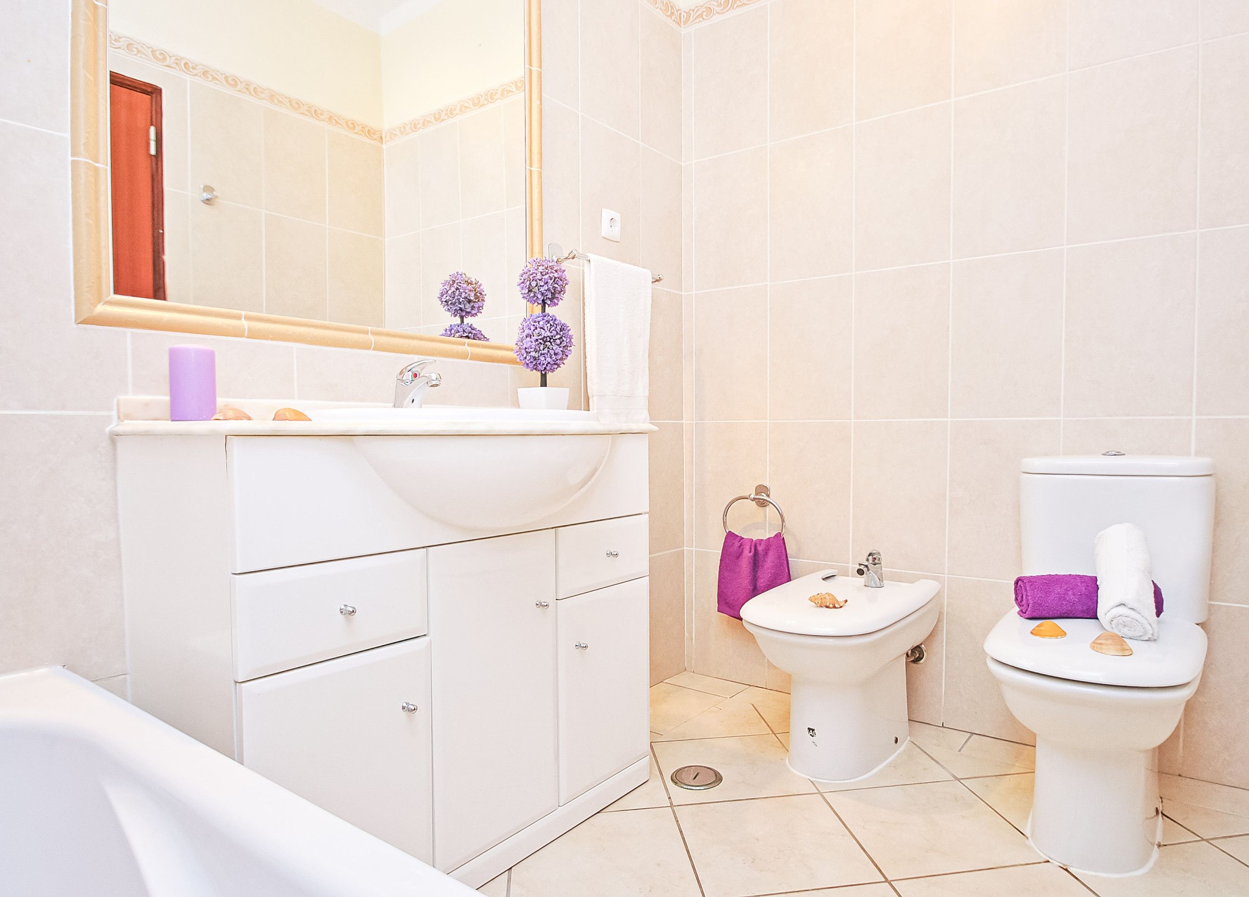 Ein Badezimmer mit weißem Waschbecken, Spiegel, Waschtisch, Toilette und Badewanne.
