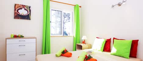 Une chambre d’hôtel avec un lit, une table de chevet avec une lampe, une commode et une fenêtre avec des rideaux.