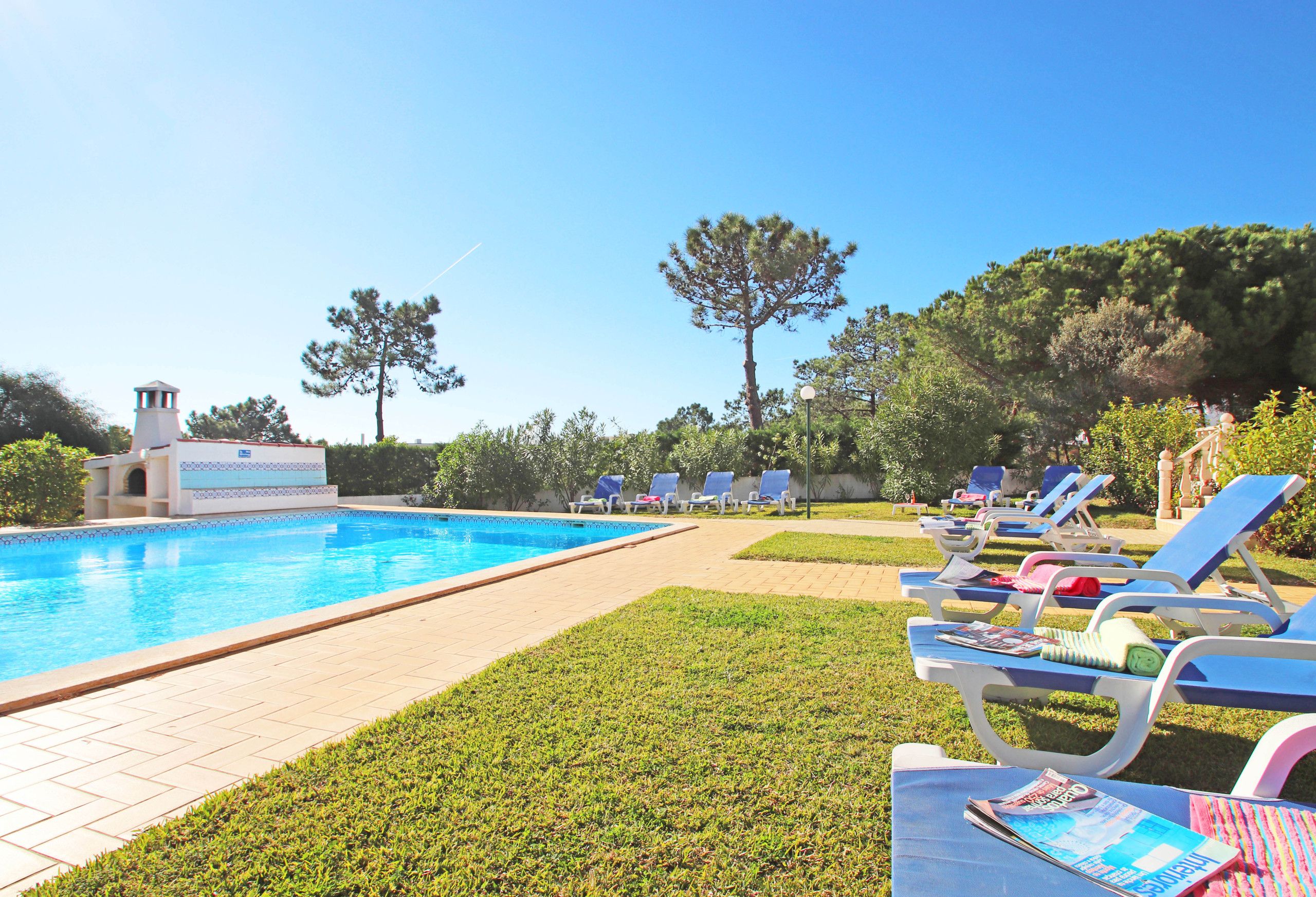 Une piscine avec des chaises longues et un petit bâtiment doté d’une tour.