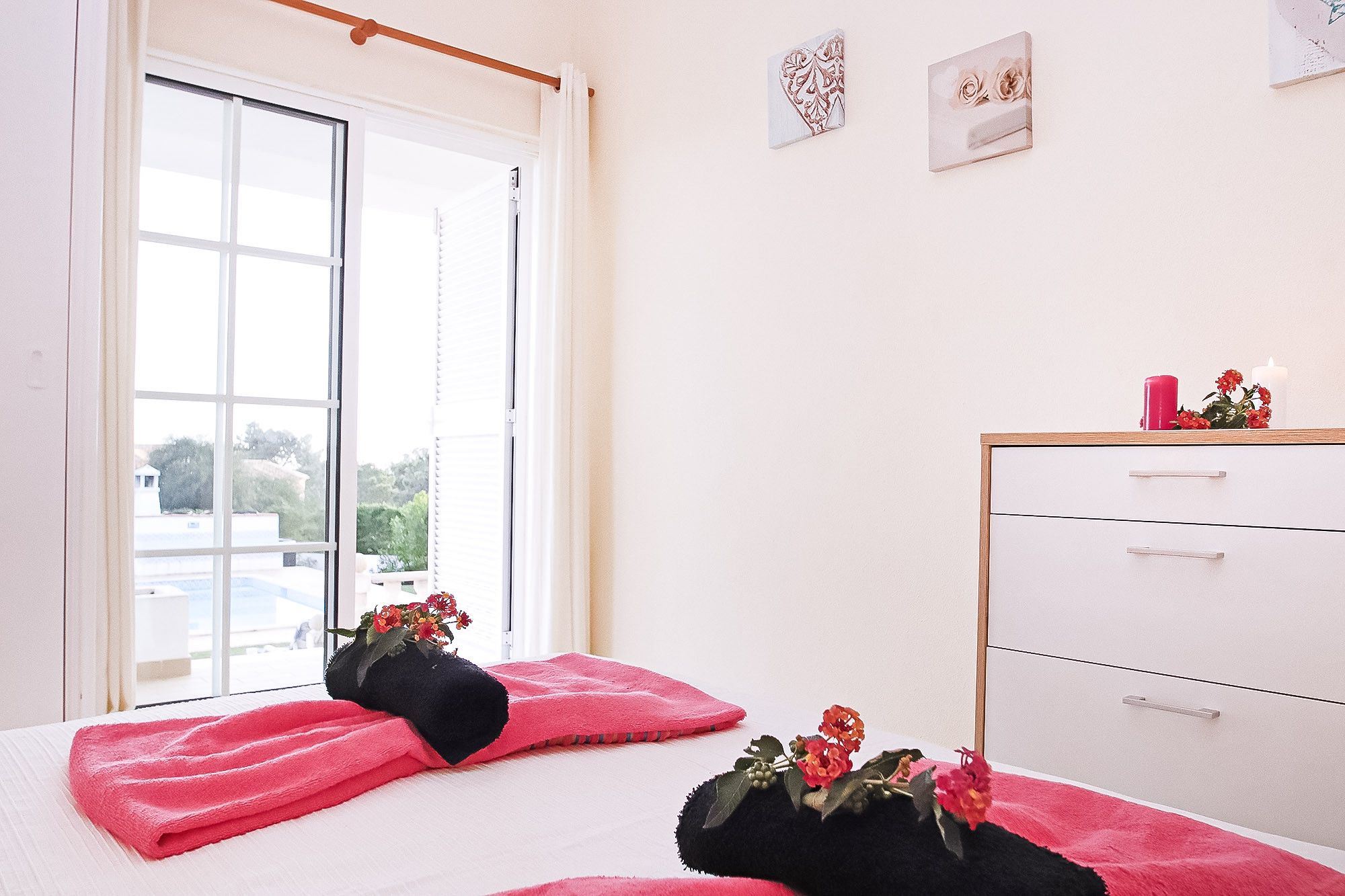 Un dormitorio con cama, ventana, cómoda y una obra de arte colgada en la pared.