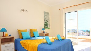 Ein Schlafzimmer mit Bett, Nachttischen, einem Gemälde und einem Balkon mit Geländer.