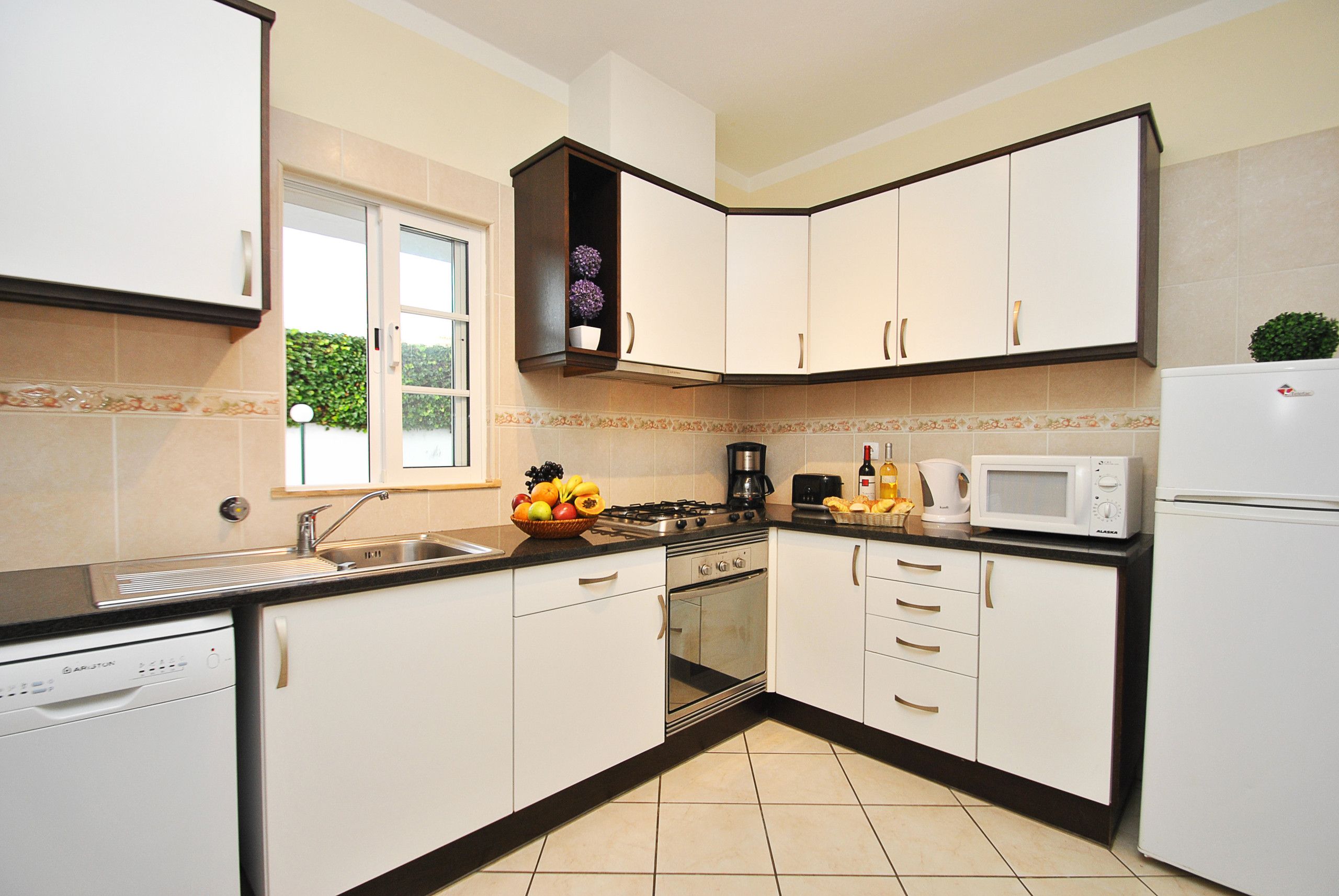 Een moderne keuken met witte kastjes, een vaatwasser, een kookplaat en een magnetron.