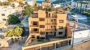 Un immeuble à plusieurs étages doté de balcons, d’un espace de stationnement et offrant une vue sur la mer.