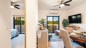 Un salon moderne comprenant un coin repas, un ventilateur de plafond et un téléviseur à écran plat fixé au mur.