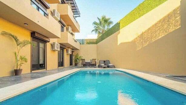 Une piscine avec des chaises longues et une plante en pot.