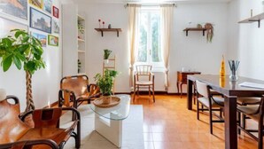 A cozy living room with a wooden floor, leather chairs, a glass coffee table, and a dining area with a wooden table and chairs. - Cozy Apartment in the Heart of Rome- St. Peter's & Vatican (Roma)