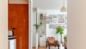 A hallway with a tiled floor, a refrigerator, a chair, a table, and a hanging light fixture. - Cozy Apartment in the Heart of Rome- St. Peter's & Vatican (Roma)