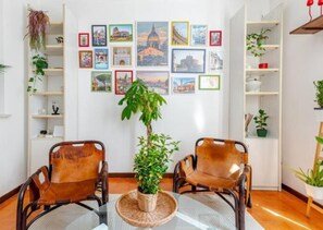 Una habitació amb dues butaques de pell, una taula central amb un farciment trenat i una paret decorada amb quadres de diversos monuments.