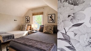 A bedroom with two single beds, a window, and a floral wallpaper on one wall.