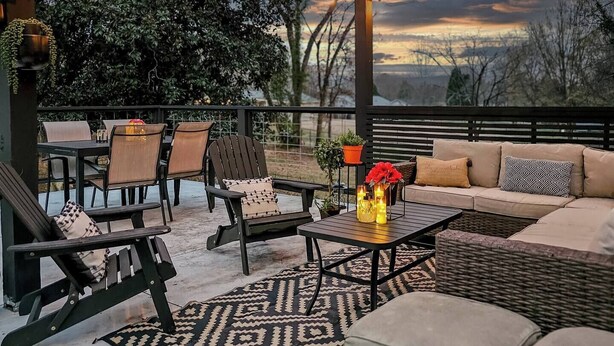 Een terras buiten met een bank, stoelen en een tafel.