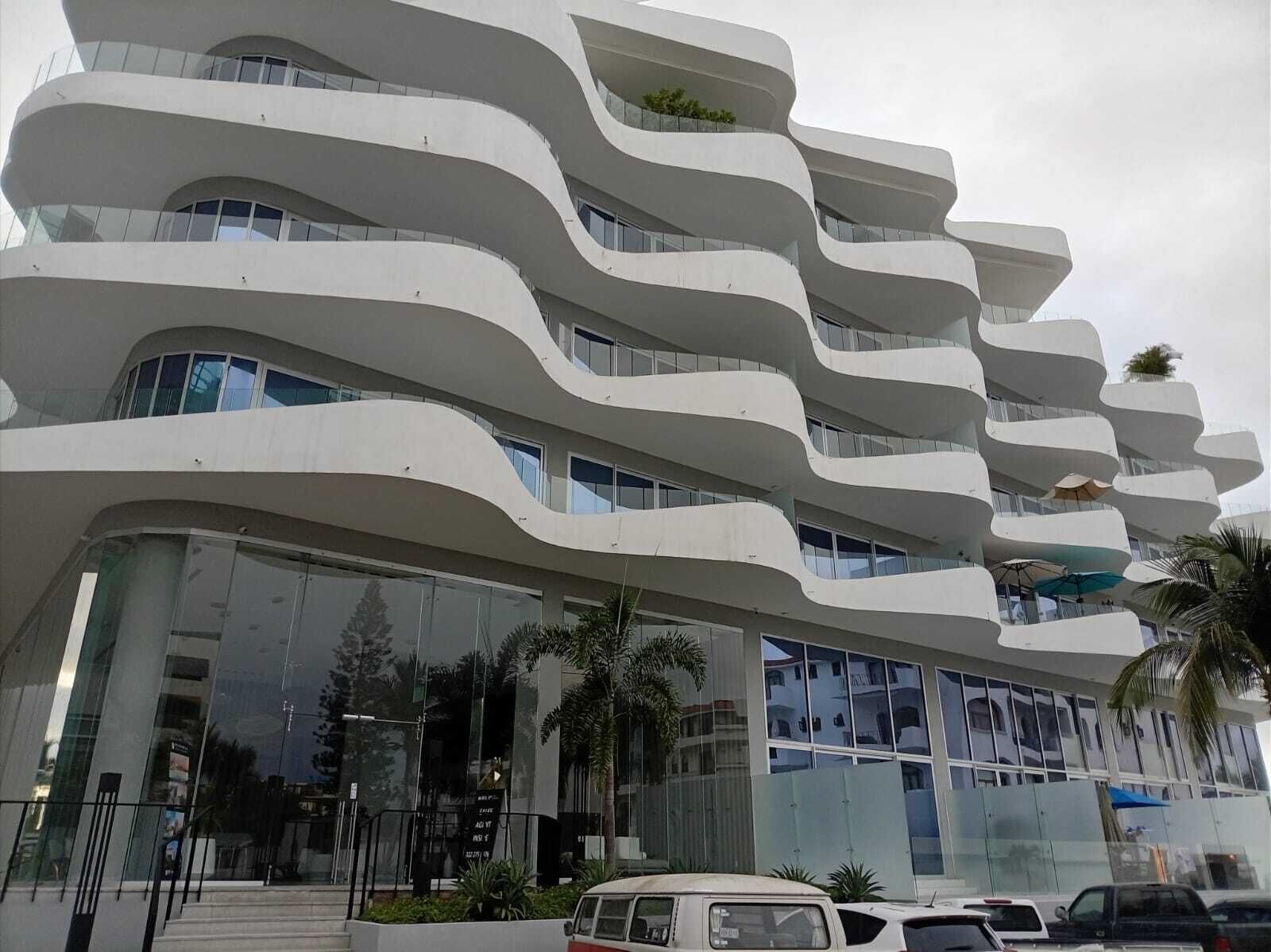 Un edificio moderno con un diseño arquitectónico ondulado, que cuenta con varios balcones y ventanas amplias.