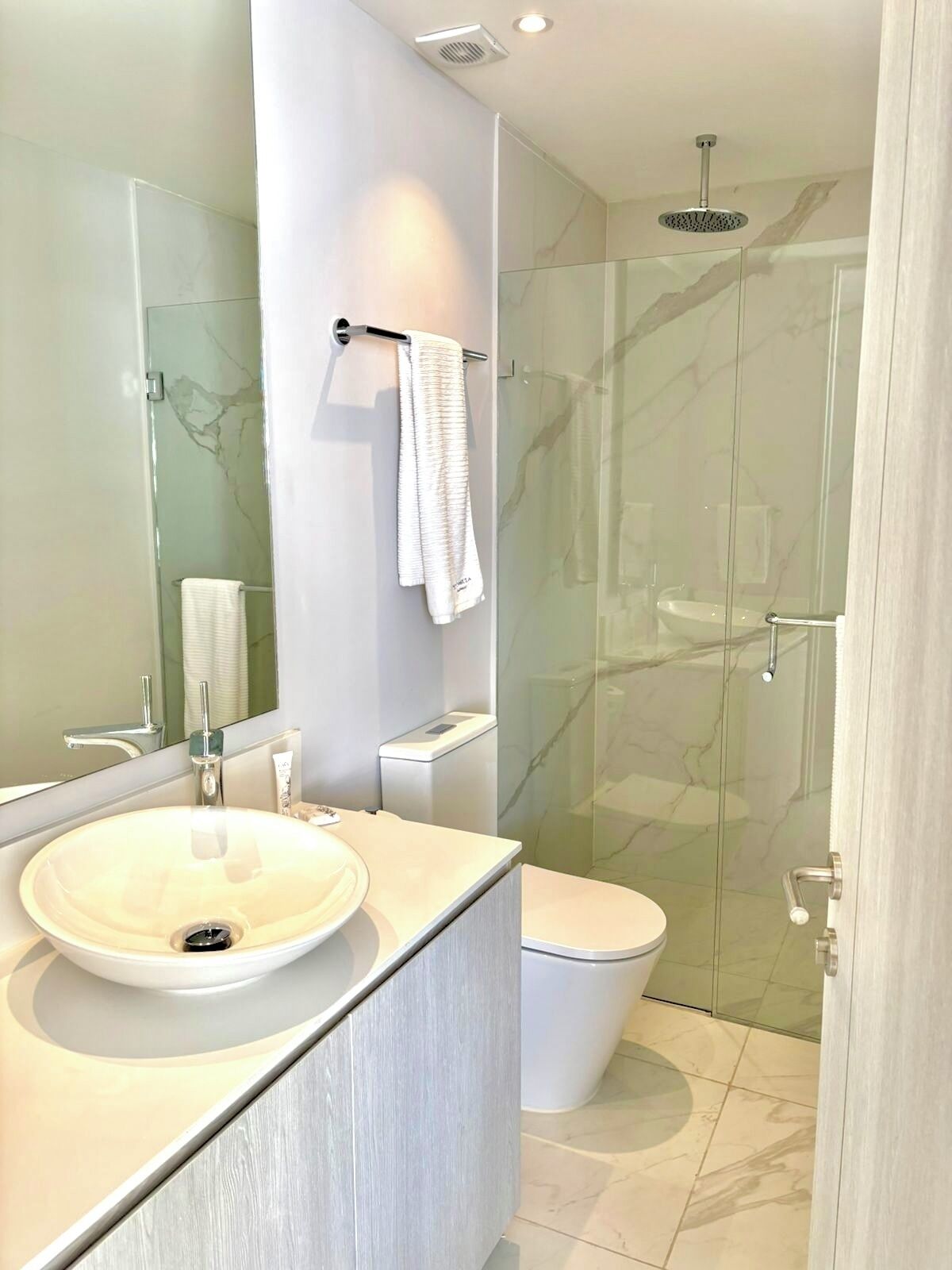 A modern bathroom with a glass-enclosed shower, a white sink, and a toilet.