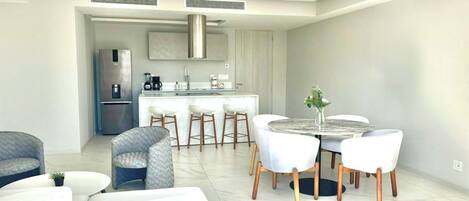 A modern living room with a dining area, a kitchen, and a large window.