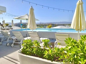 A rooftop pool area with lounge chairs and umbrellas, surrounded by greenery. - Park Life Nautico Vacational (Nuevo Nayarit)