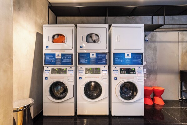 A row of three front-loading washing machines with digital displays, arranged in a commercial setting.