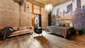 Une chambre avec une fresque murale représentant un paysage urbain, un lit, un canapé et un bureau.