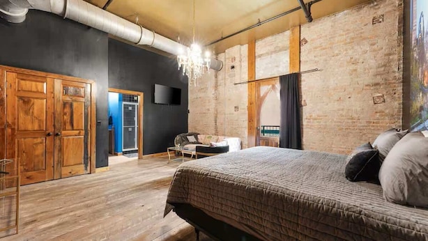 Une chambre avec un grand lit, une armoire en bois et un mur en briques.