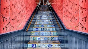 Un escalier aux marches recouvertes de carreaux colorés et doté d’une main courante en bois, menant à un palier.
