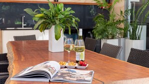 A wooden table with a magazine, two wine glasses, a bottle of wine, and a plate with food and strawberries. - Marine Adventures – tranquil blue waters and white beaches of Jervis Bay (Callala Bay)