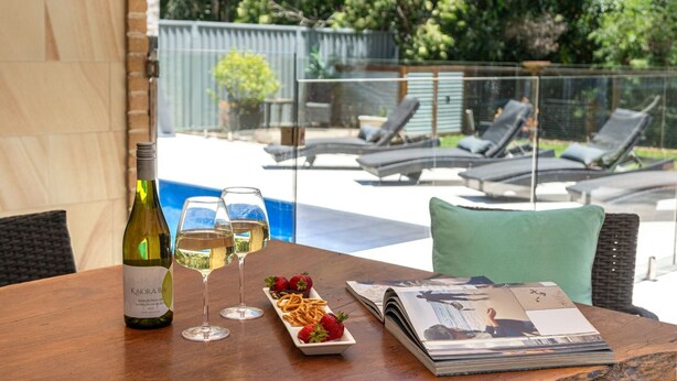 A table with a bottle of wine, two glasses, a plate of strawberries and pretzels, and a magazine. - Marine Adventures – tranquil blue waters and white beaches of Jervis Bay (Callala Bay)