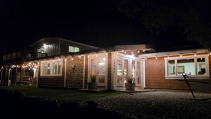 Un bâtiment à deux étages doté d’un patio couvert, de détails en pierre et de guirlandes lumineuses.