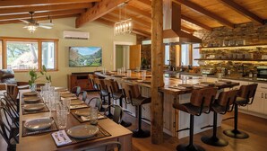 Une cuisine spacieuse dotée d’un grand îlot central, de poutres en bois et d’un mur en pierre.