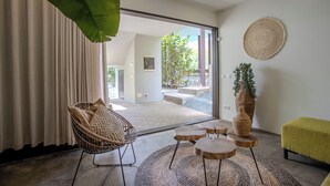 A modern interior with a wicker chair, a round table, and a green bench. - Unique architectural villa with private pool on nature resort (Sint Michiel)
