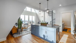 Una cocina moderna con una isla central, suelo de madera y vistas al exterior.