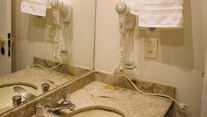 A bathroom with a sink, two mirrors, and two hair dryers mounted on the wall. - piscina academia e manobrista (São Paulo)