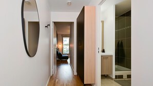 Un baño moderno con ducha, inodoro y lavamanos. Hay un espejo en la pared y una puerta que da a otra habitación.