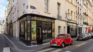 Ein historischer Ladenfront mit dem Schild "BOULANGERIE 29" und einem roten Oldtimer davor.
