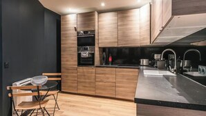 Eine moderne Küche mit Holzausstattung, einem eingebauten Ofen und einer Edelstahl-Spüle.