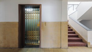 Una escalera con barandilla y una puerta con reja de metal.