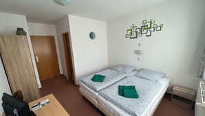 Ett hotellrum med en säng, ett skrivbord med en dator, en garderob och en väggdekoration.