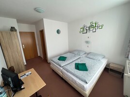 Quarto de hotel com cama, escrivaninha com computador, guarda-roupa e um adorno na parede.