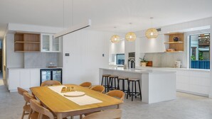 Una cocina moderna con armarios blancos, una mesa de comedor de madera y taburetes de bar.