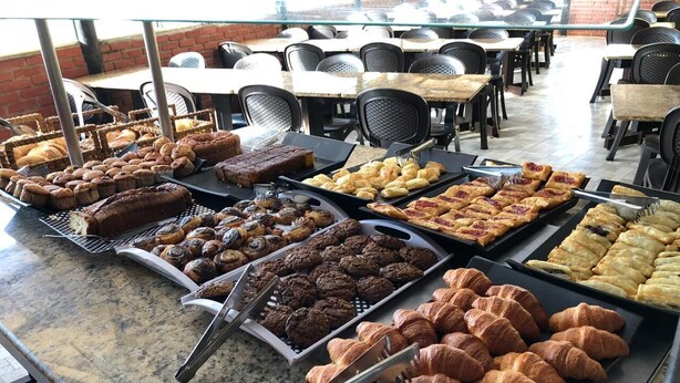 A buffet with various baked goods including bread, pastries, and cookies. - Pousada do Francês (Bertioga)