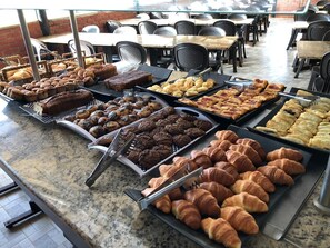 Un buffet proposant une variété de produits de boulangerie, notamment du pain, des viennoiseries et des biscuits.