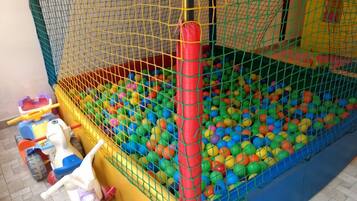 A children's play area with a ball pit, a slide, and a small toy car.