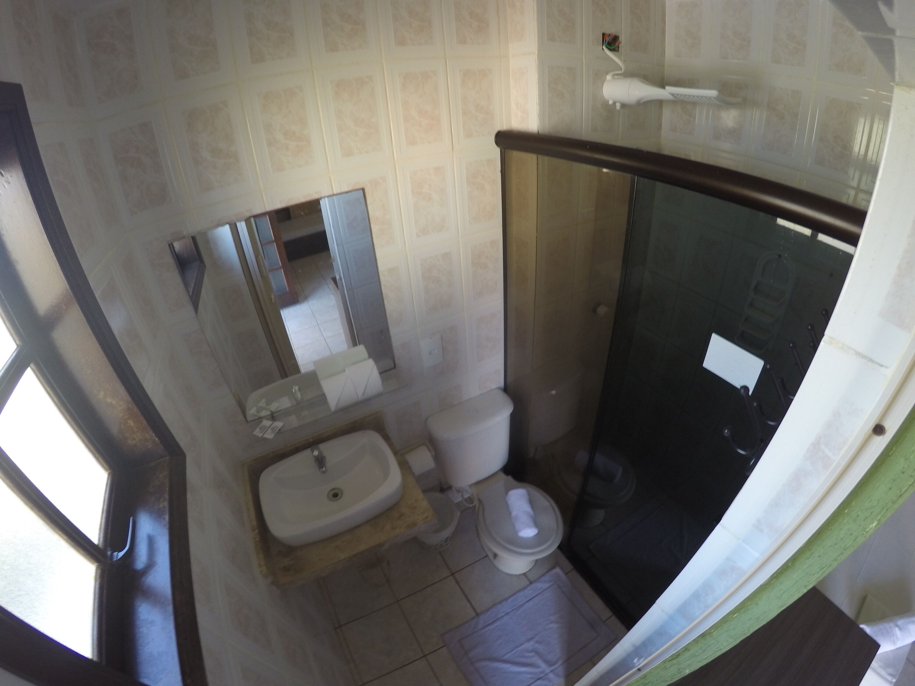 A compact bathroom with a sink, toilet, and shower area.