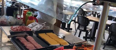 Un bufé con diversas opciones de comida, incluyendo carnes, quesos y frutas.