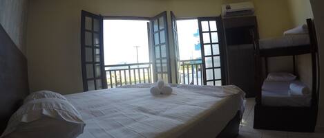 Una habitación de hotel con cama, ventana, equipo de aire acondicionado y literas.