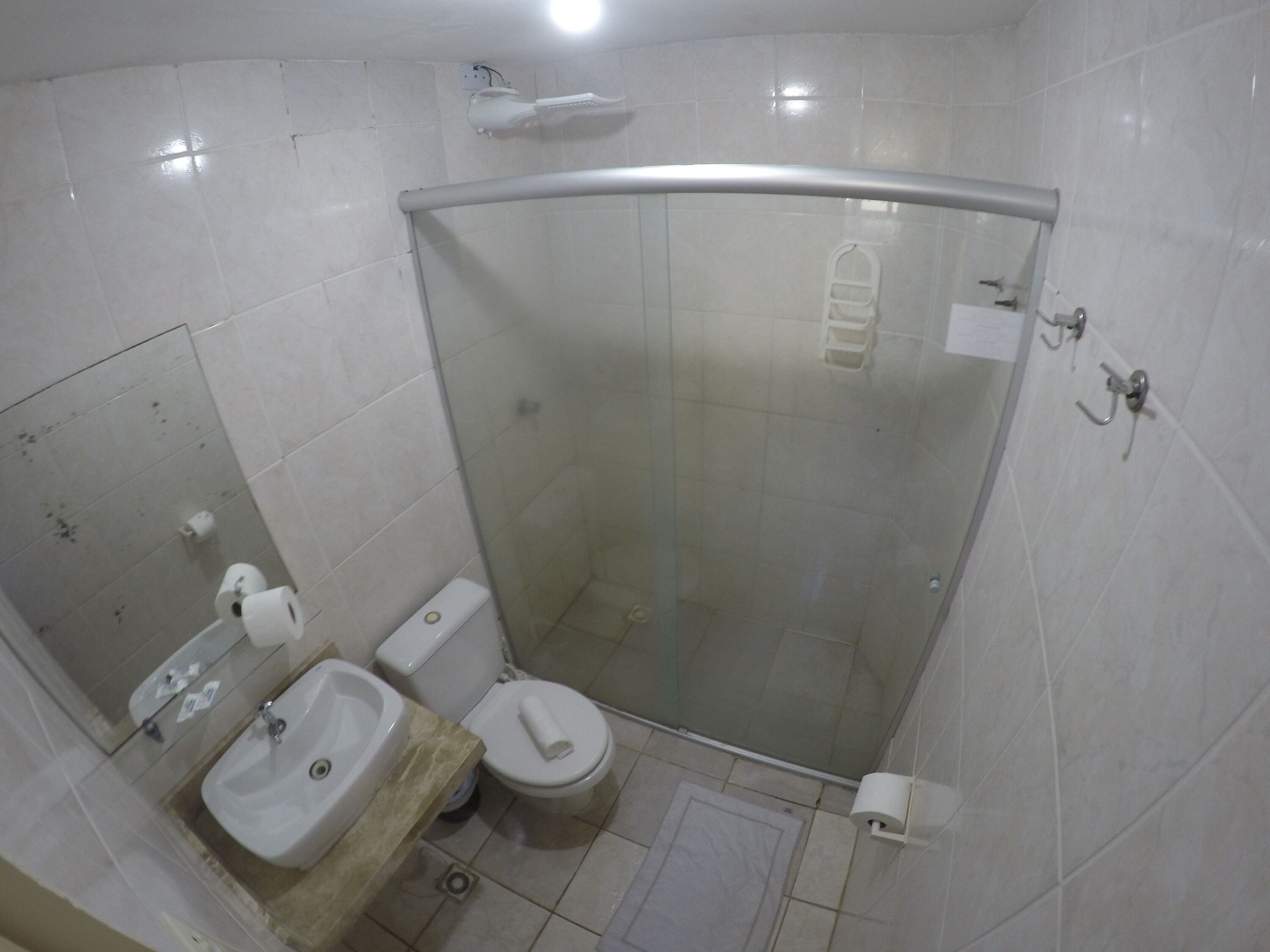 Une salle de bain avec douche, toilettes et lavabo.