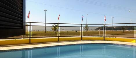 A swimming pool with a view of a beach and flags.