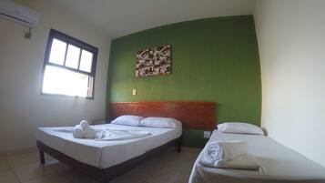 Habitación de hotel con dos camas, una pared verde decorativa, una ventana y una obra de arte colgada en la pared.