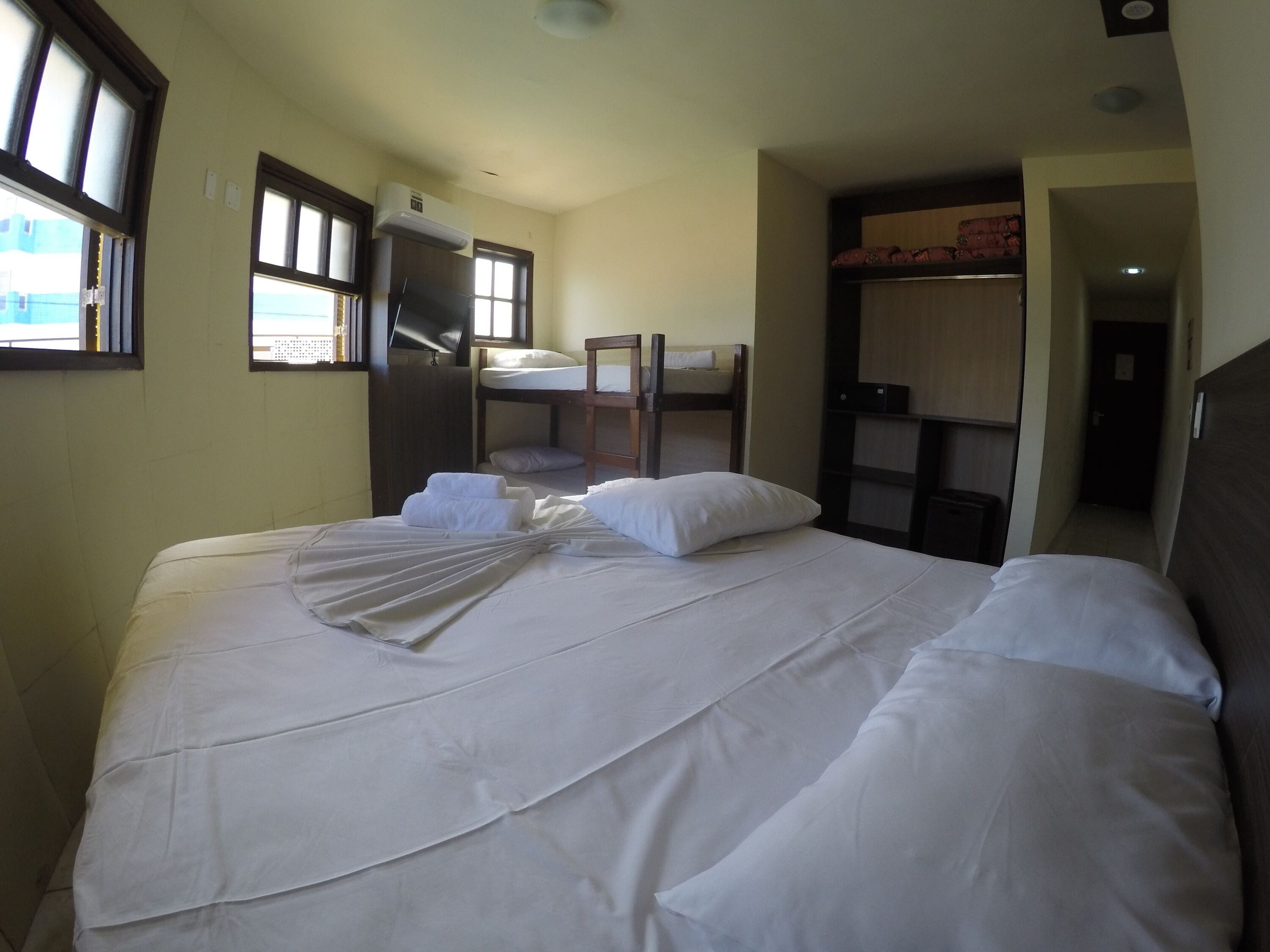 A hotel room with a bed, a bunk bed, a desk, and a wardrobe.