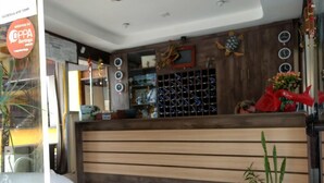 A reception area with a wooden counter, a clock, and a potted plant. - Pousada do Francês (Bertioga)
