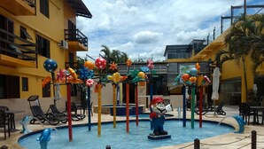 A pool area with a Mario statue, colorful flower decorations, and lounge chairs. - Pousada do Francês (Bertioga)